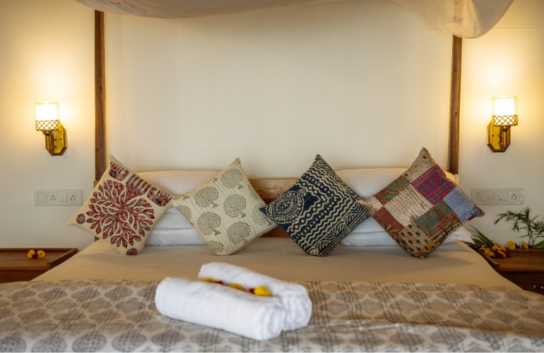 Ravi Yoga King Room King bed with colourful cushions, towels and flower details